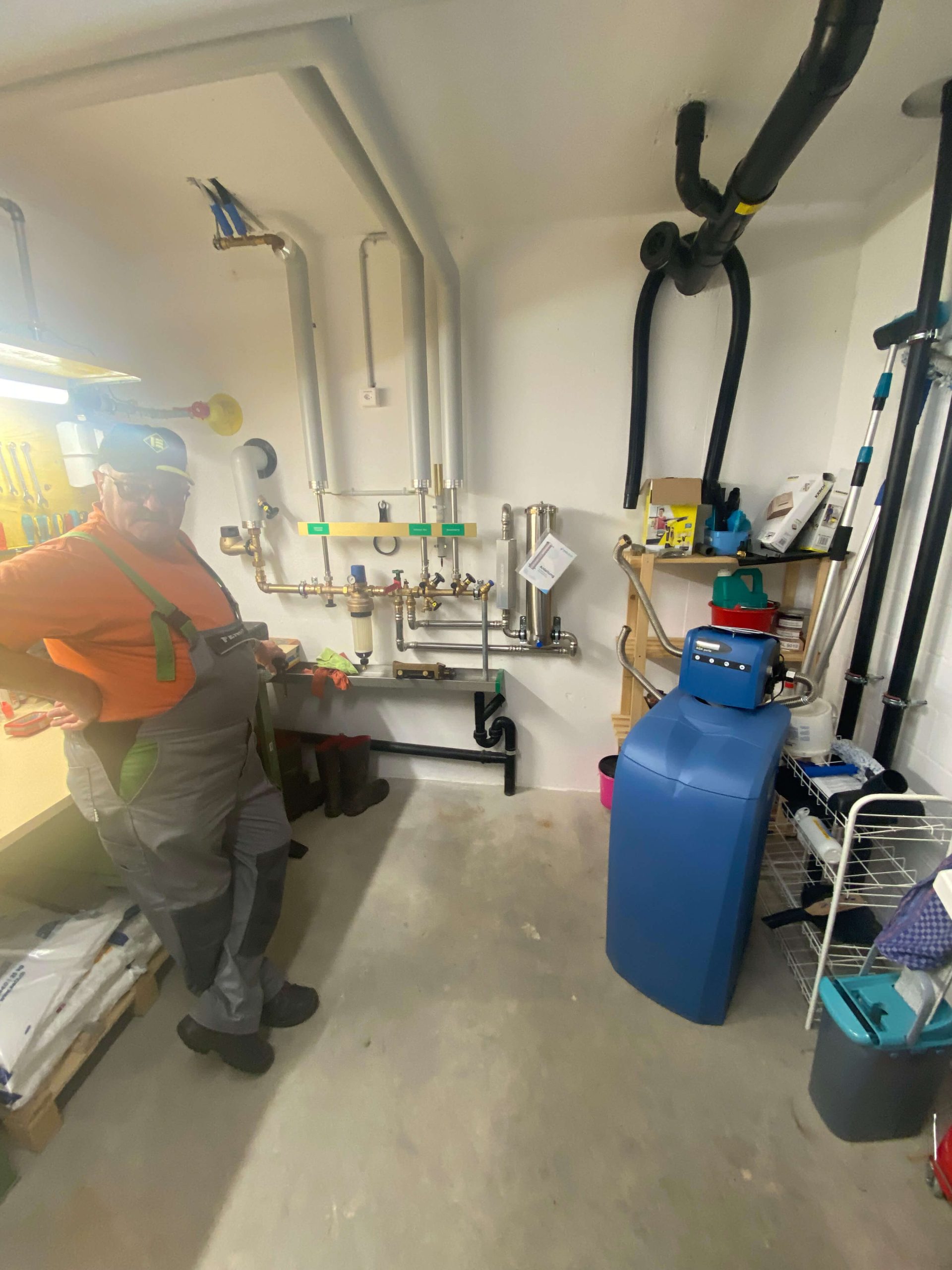 Instalador junto a um descalcificador de água à base de sal na sala de plantas. A Evodrop oferece-lhe uma alternativa mais sustentável sem sal.