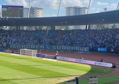 Fussballspiel im Stadion mit der Zürcher Südkurve und Evodrop-Werbung auf der LED-Bande – Nachhaltige Wassertechnologie im Schweizer Sport.